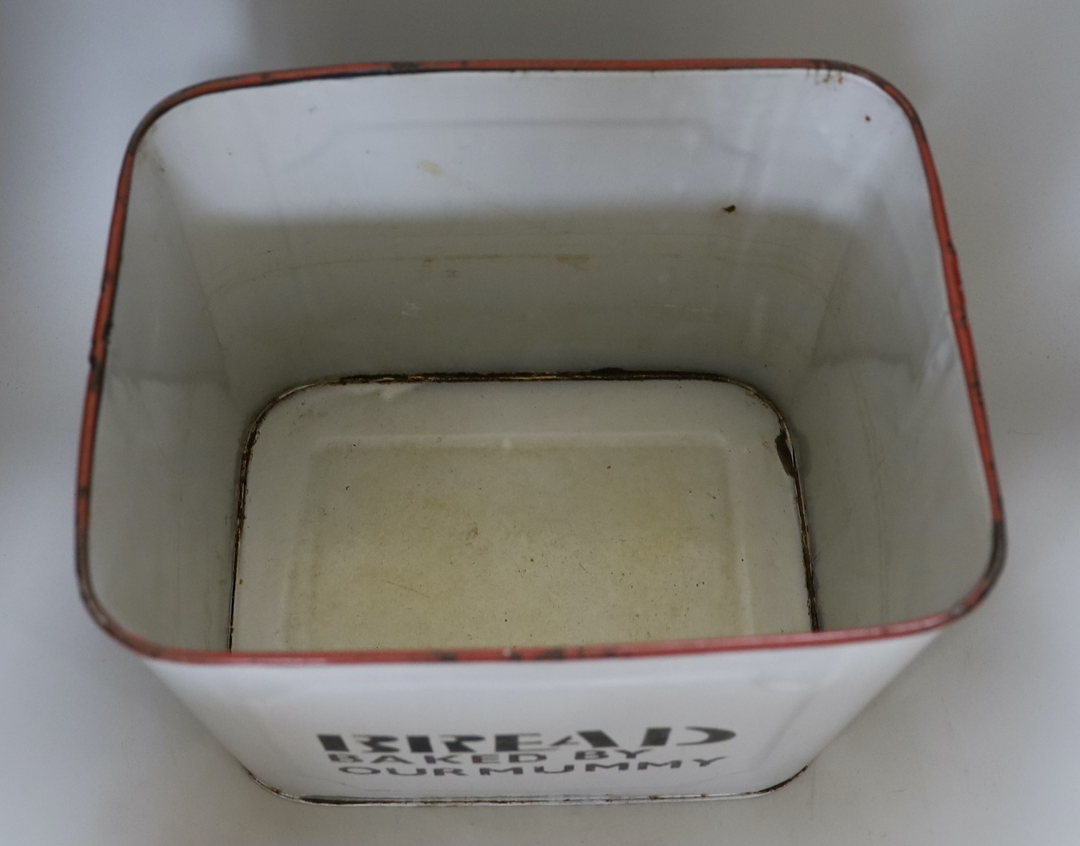 A vintage white enamel bread bin and cover, printed “Bread Baked By our Mummy”